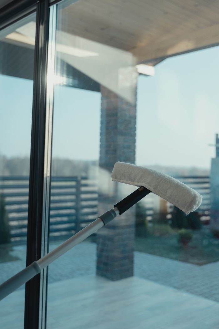 Un outil de nettoyage moderne utilisé pour laver une grande fenêtre en verre avec une vue dégagée sur l’extérieur.